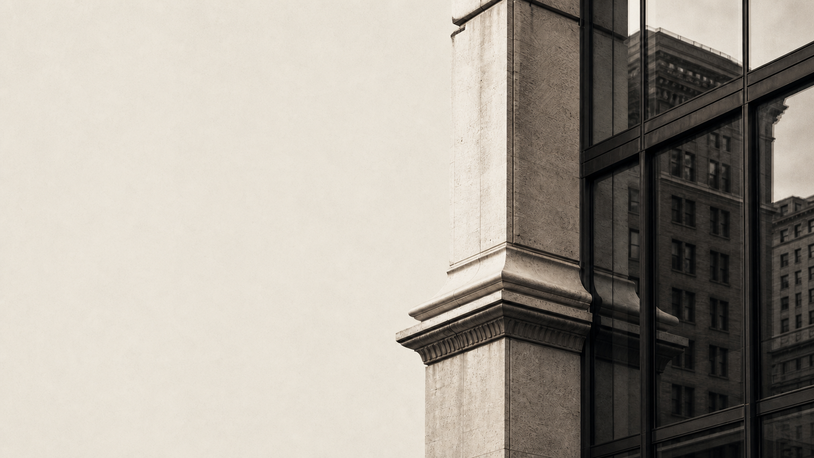 Classical limestone column beside a contemporary glass facade